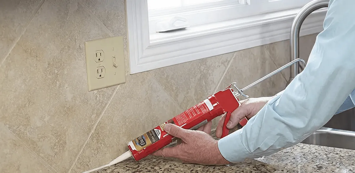 Handyman applying caulk along a kitchen backsplash and countertop seam in Little Rock, AR